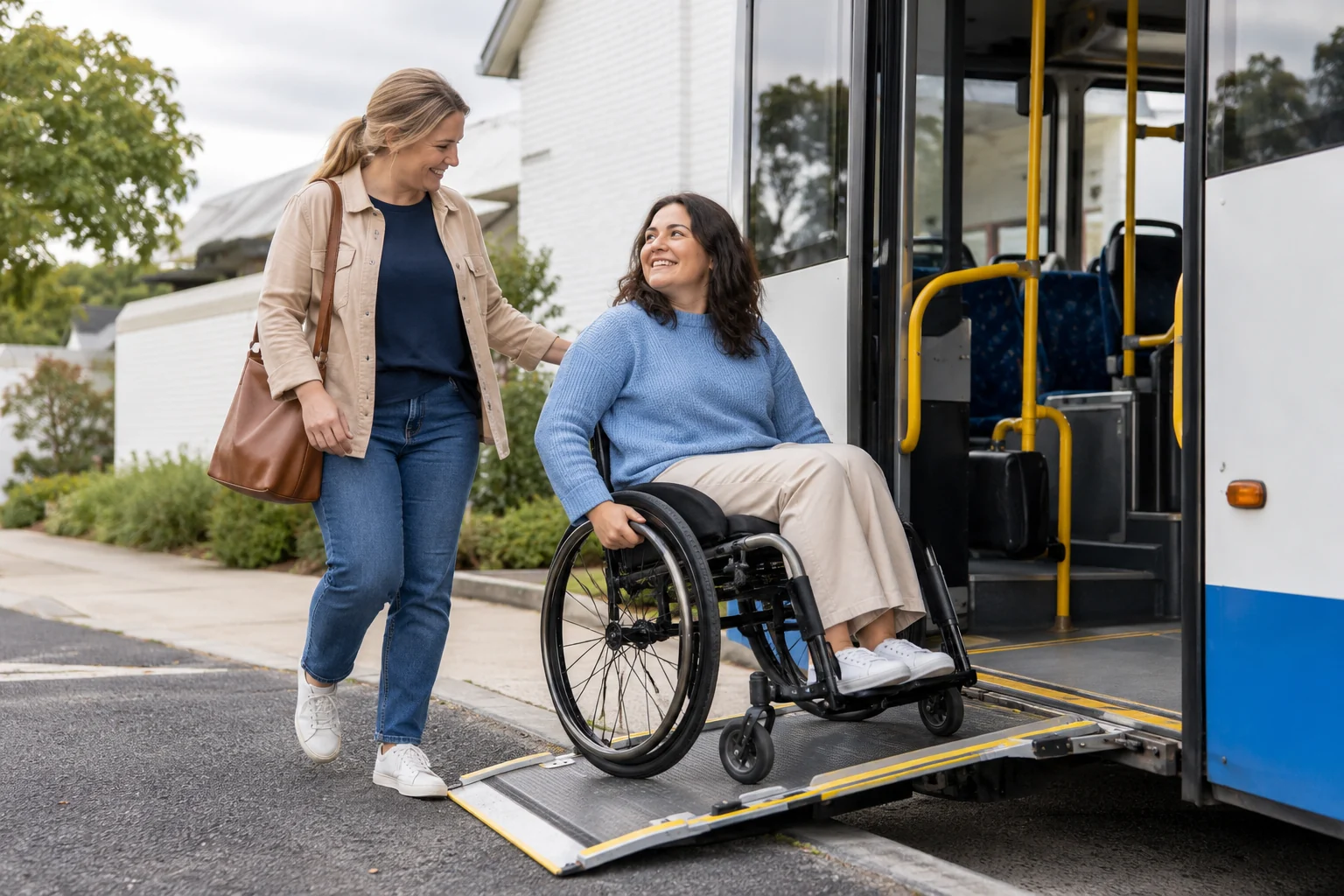 A woman using a wheelchair and a companion near an accessible bus