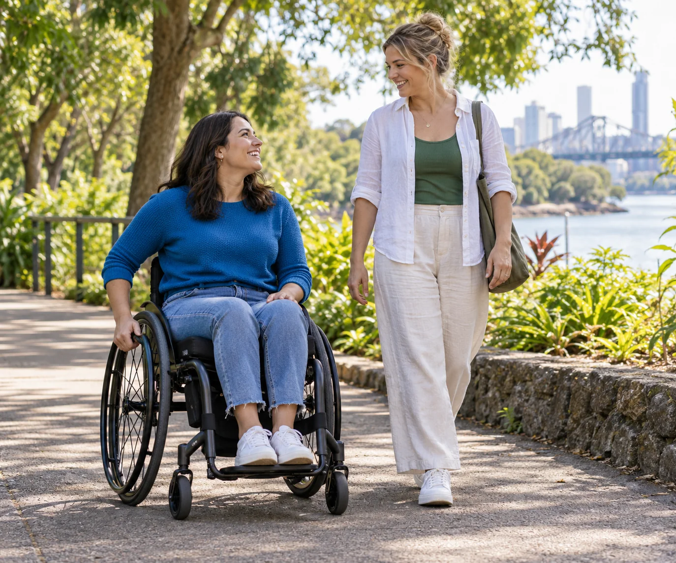 A woman using a wheelchair talks with a companion in a leafy park